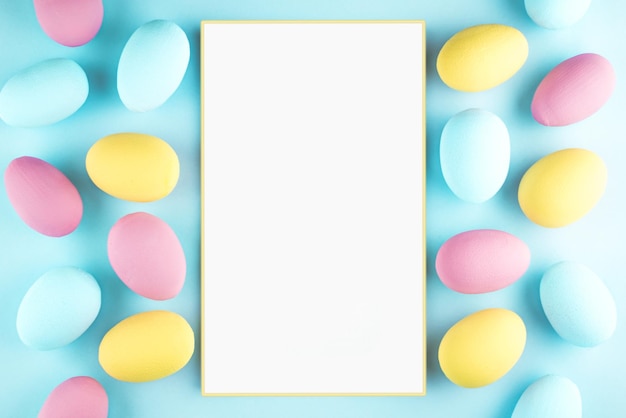 Multicolored eggs lie on a blue background and next to it is a white sheet of paper