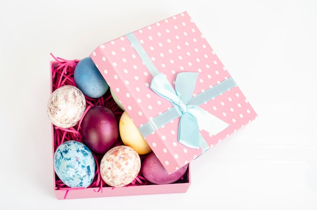 Multicolored eggs in open gift box. Concept of the Happy Easter holiday, greeting card template. Studio Photo