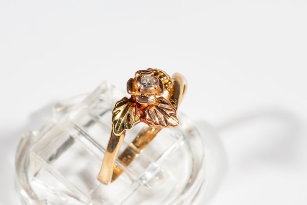 Multicolored gold diamond ring on a white background flower and grape leaves in a frame