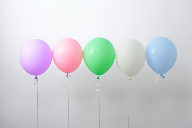 Multicolored helium balloons in row on white background festive mood copy space