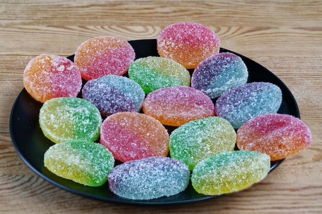 Multicolored jelly marmalade on a black plate background