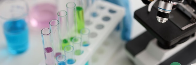 Multicolored laboratory test tubes and microscope in laboratory analysis of chemical fluids in