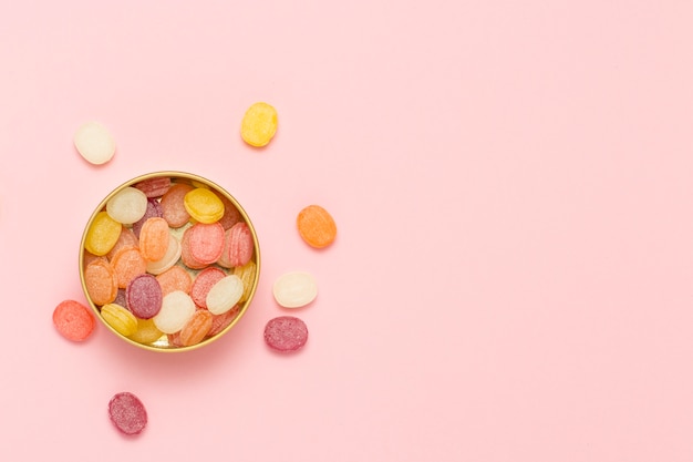 Multicolored lollipops in a round can on a gently pink background. Concept of sweets and candies. Sweet gift. Sweet love. Fruit flavor.