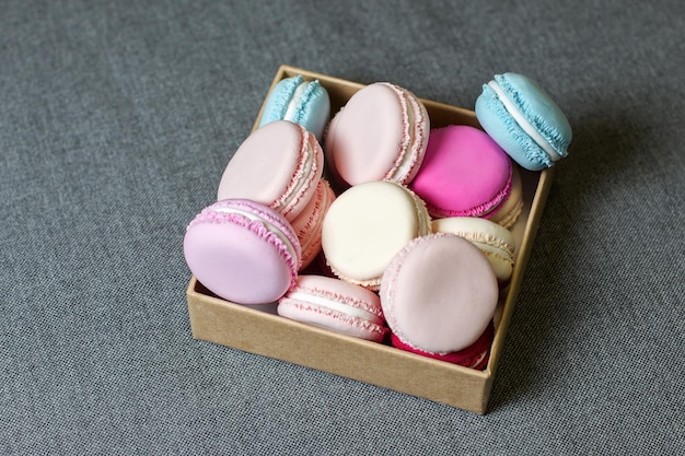 Multicolored macaron from polymer clay in a box on the background of gray fabric