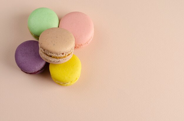 Multicolored macaroons or macarons on pastel beige. 