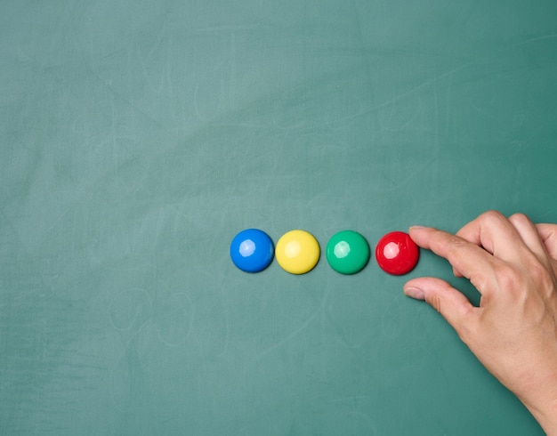 Multicolored magnets on a green chalk board