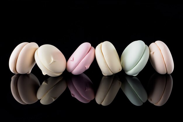 Multicolored marshmallow isolated on a black background with reflection, pastel. Beautiful and colorful macaroons background. Bright background or splash screen. Sweets creative trend concept.