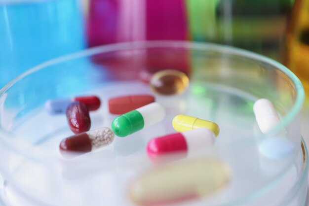 Multicolored medical pills lie on glass test tube pharmaceutical industry concept