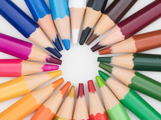 Multicolored pencils lie on a white background bright colored pencils rotate around themselves