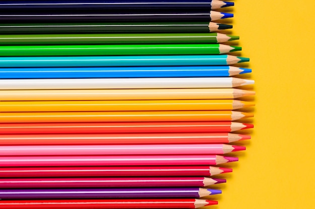 Multicolored pencils on a yellow background Color pencils set row wooden color pencils for drawing