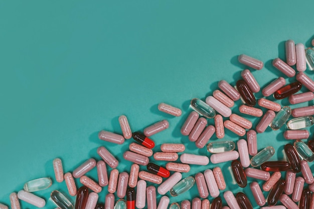 Multicolored pills and capsules on a green background