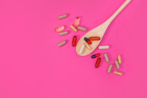 Multicolored pills and capsules on a pink background