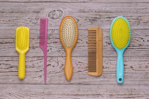 Multicolored plastic and wooden combs on a wooden background Accessories for hair care