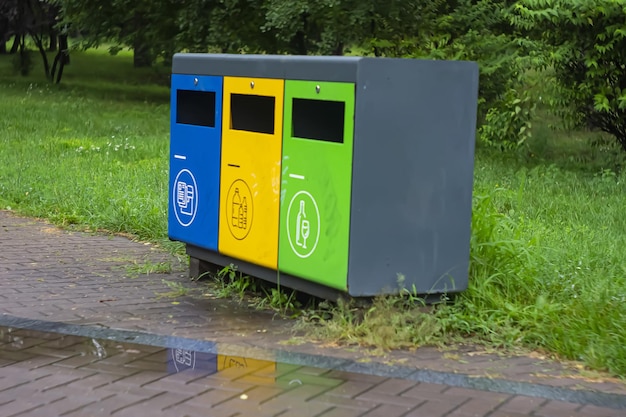 Multicolored recycling bins in the park Outdoor garbage containers for plastic paper glass Sustainable lifestyle concept