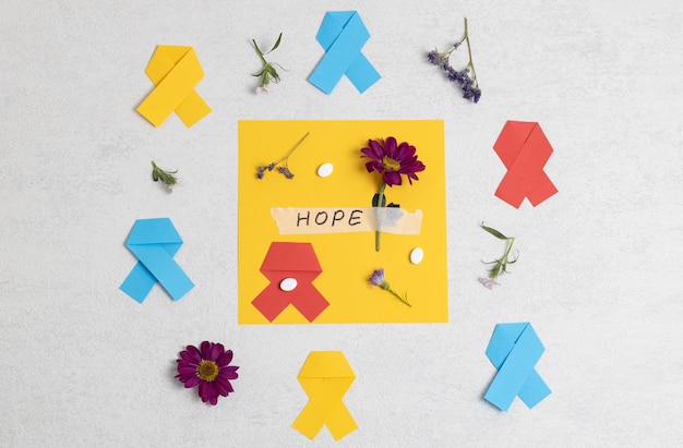 Multicolored ribbons flowers the word hope and pills on stone