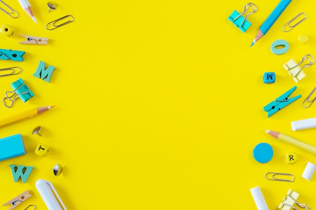 Multicolored school supplies on yellow background with copy space