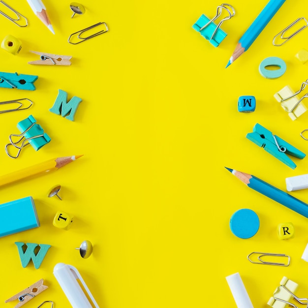 Multicolored school supplies on yellow background with copy space.