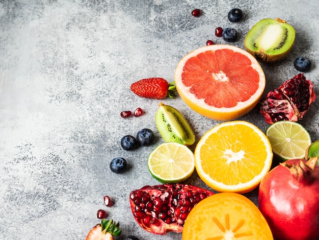 Multicolored seasonal healthy natural fruit composition with persimmon, blueberries, orange, kiwi, strawberries, grapefruit, pomegranate, orange slices. Copy space