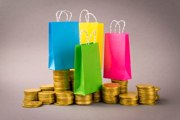 Multicolored shopbags bundle of dollars and coins on a gray background Shopping concept