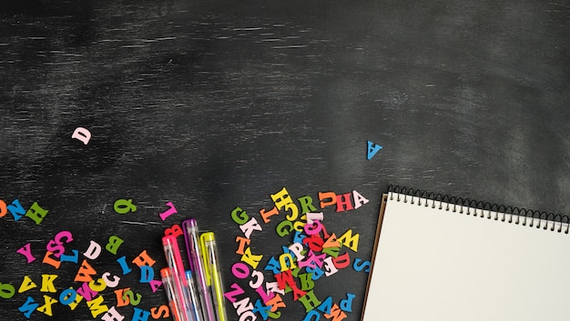 Multicolored small wooden letters of the English alphabet and paper notebook 