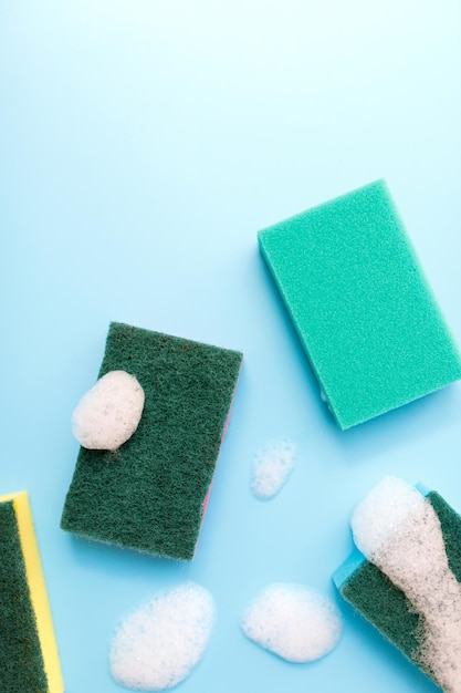 Multicolored sponges for cleaning on a blue background Space for text