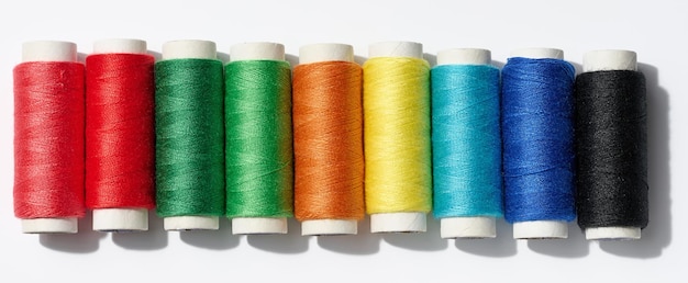 Multicolored spools of sewing threads on a white background top view