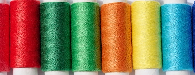 Multicolored spools of sewing threads on a white background top view