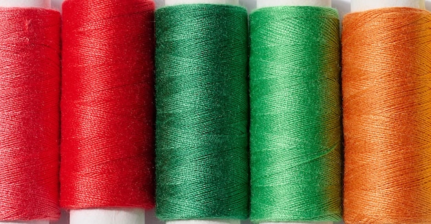 Multicolored spools of sewing threads on a white background top view