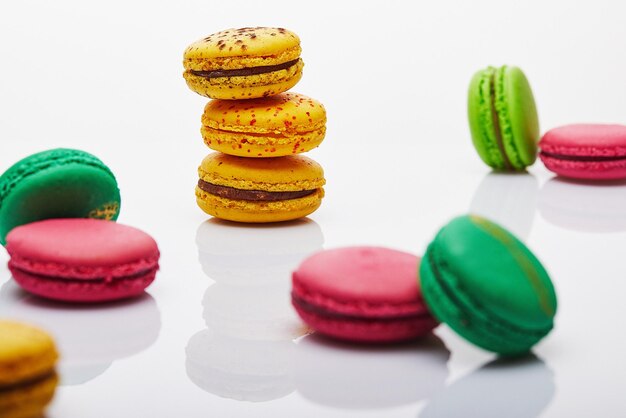 Multicolored stacked and separated macarons displayed on white background with reflection