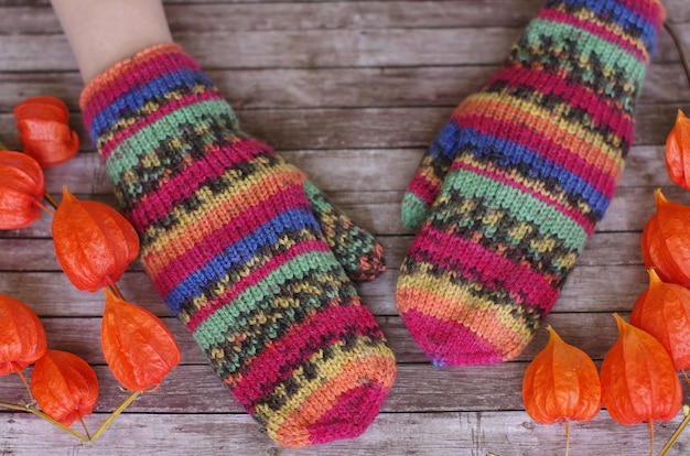 Multicolored striped mittens on a wooden  with an orange decor