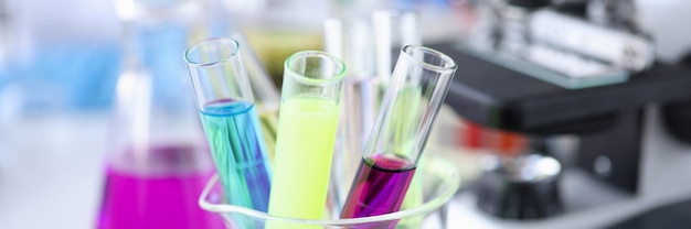 Multicolored test tubes with liquids stand next to microscope chemical research substances