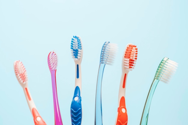 Multicolored toothbrushes on blue background copy space