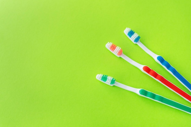 Multicolored toothbrushes on a green background the concept of dental care and oral hygiene Place for an inscription