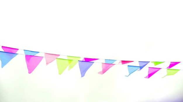 Multicolored triangular flags hang on a string and flutter in the wind against a cloudy cloudy sky