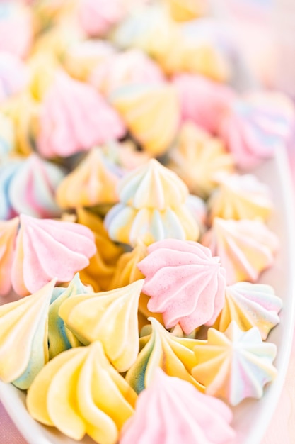 Multicolored unicorn meringue cookies on a white serving plate.