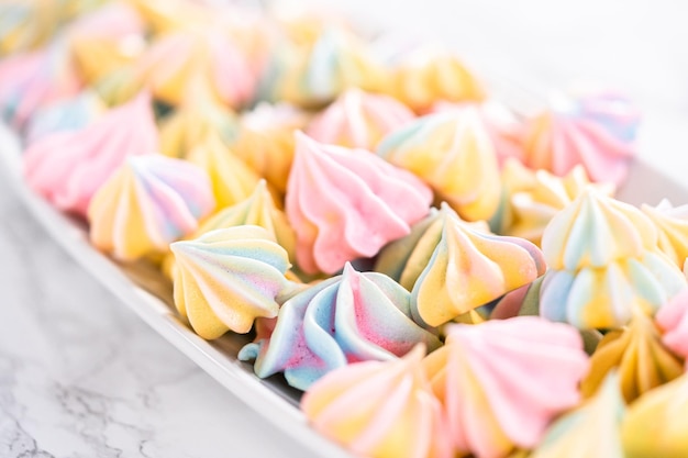 Multicolored unicorn meringue cookies on a white serving plate