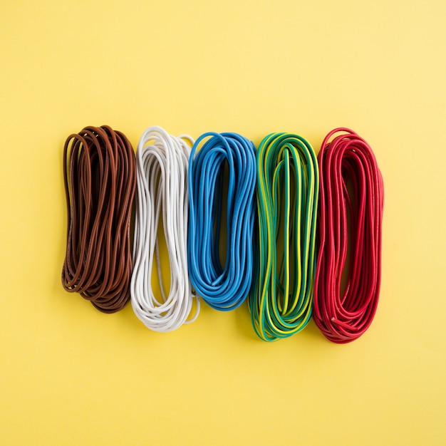 Multicolored wired arranged in a row on yellow backdrop