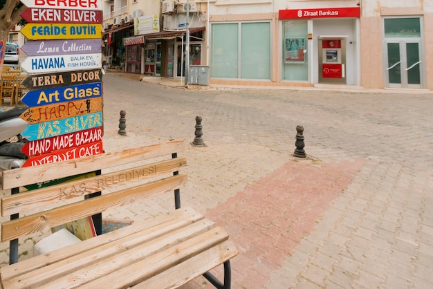 Multicolored wooden pointer with inscriptions on a city street near a wooden bench