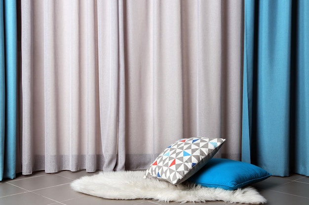 Multicoloured pillows on a carpet in a room