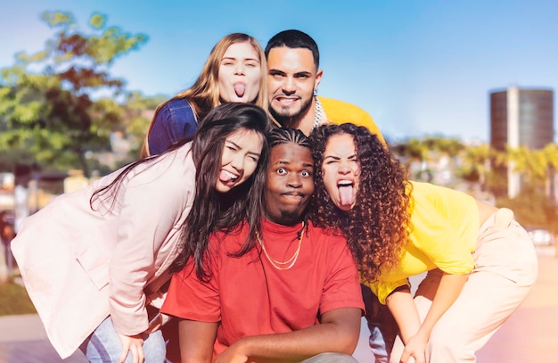 Multicultural friends taking crazy selfie sticking out tongue Young milenial people having fun