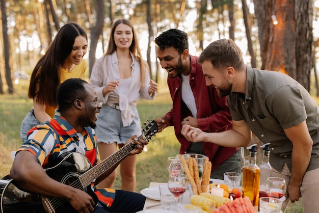 Multicultural group of people African hipster man playing guitar and friends dancing singing