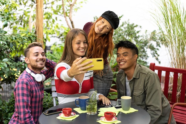 Multicultural happy friends having fun taking group selfie portrait outside in the garden during a coffee break Mixed race young people laughing together enjoying a day out on vacation