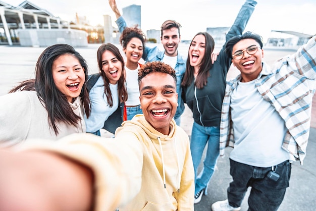 Multicultural happy friends having fun taking selfie picture on city street