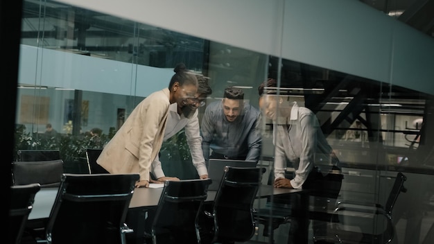 Multiethnic business team coworkers looking at laptop celebrating success in coworking yes gesture