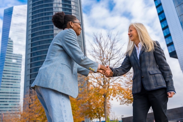 Multiethnic businesswomen and executives smiling and greeting by shaking hands in a business park