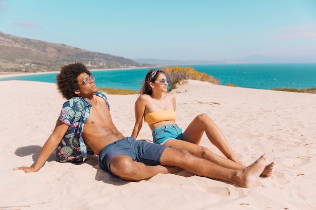 Multiethnic couple sunbathing on beach