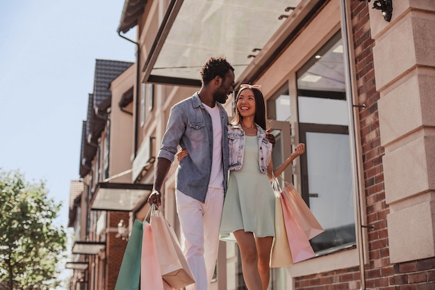 Multiethnic couple walking on the street with shopping bags at daytime