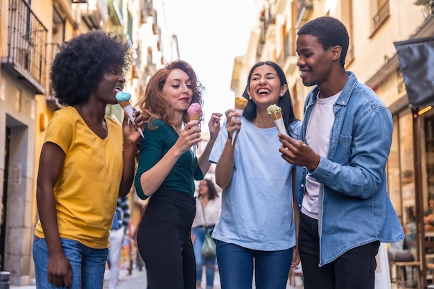 Multiethnic friends eating an ice cream cone summer fun walking down the street