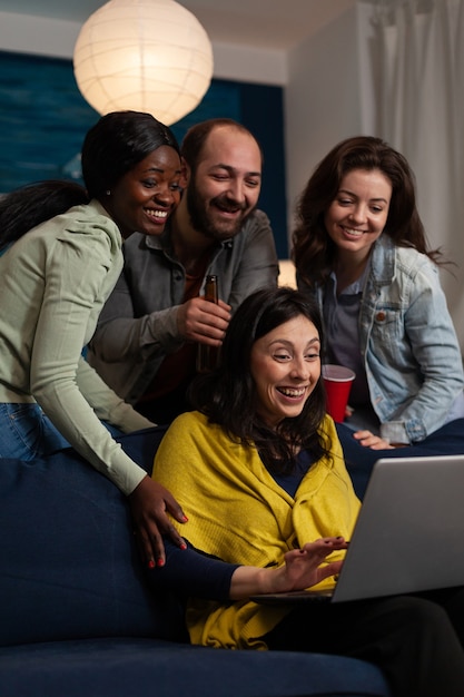 Multiethnic friends relaxing on couch laughting while watching fuuny comedy