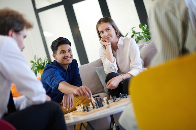 multiethnic group of business people playing chess while having a break in relaxation area at modern startup office